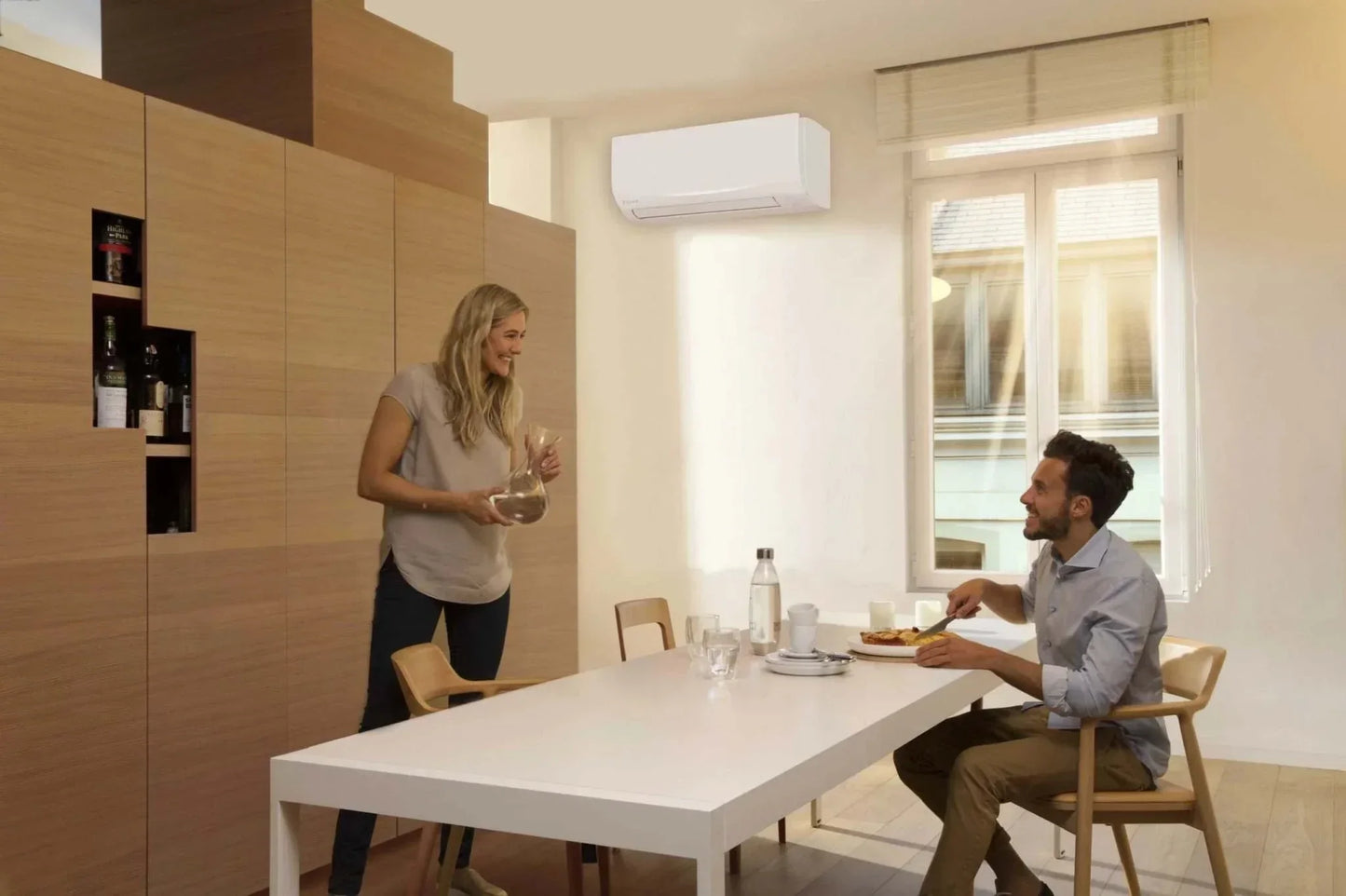 Daikin Sensira FTXF50F inverter Klimaanlage installed on wall in modern dining room with natural light and people enjoying meal