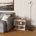 White S-shaped shelf bookcase with three tiers holding books and decorative items beside a gray sofa and floor lamp in a living room