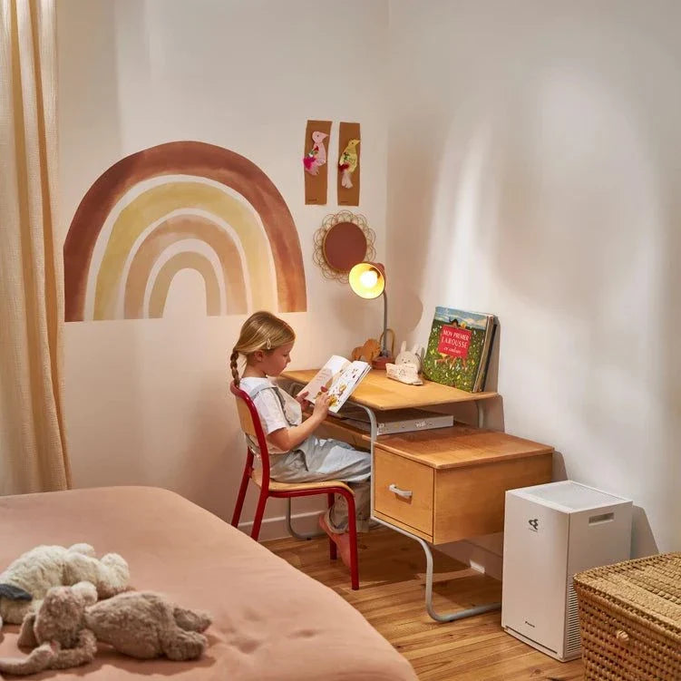 Daikin MC30Y air purifier in a cozy child's bedroom with a rainbow wall decal and wooden desk.