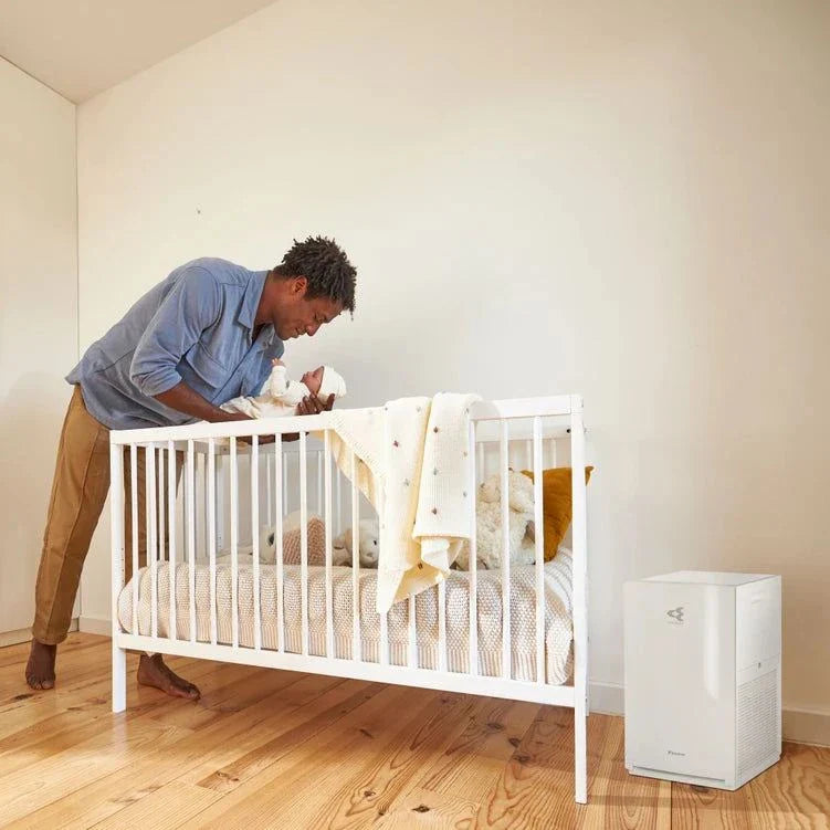 Daikin MC30Y air purifier in a nursery room beside a white crib with a man holding a baby.