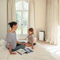 Daikin MC80Z air purifier in bright room with woman and child sitting on bed nearby