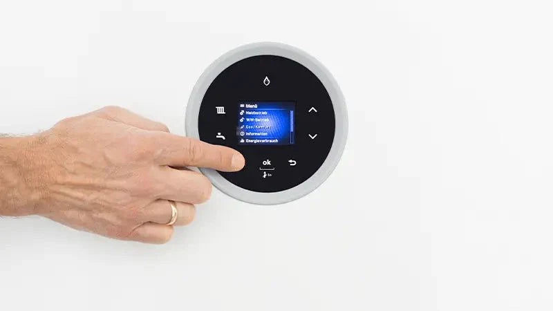 Close-up of a hand adjusting the circular touchscreen control panel of the Bosch Condens 5700i WT wall-mounted gas condensing boiler.
