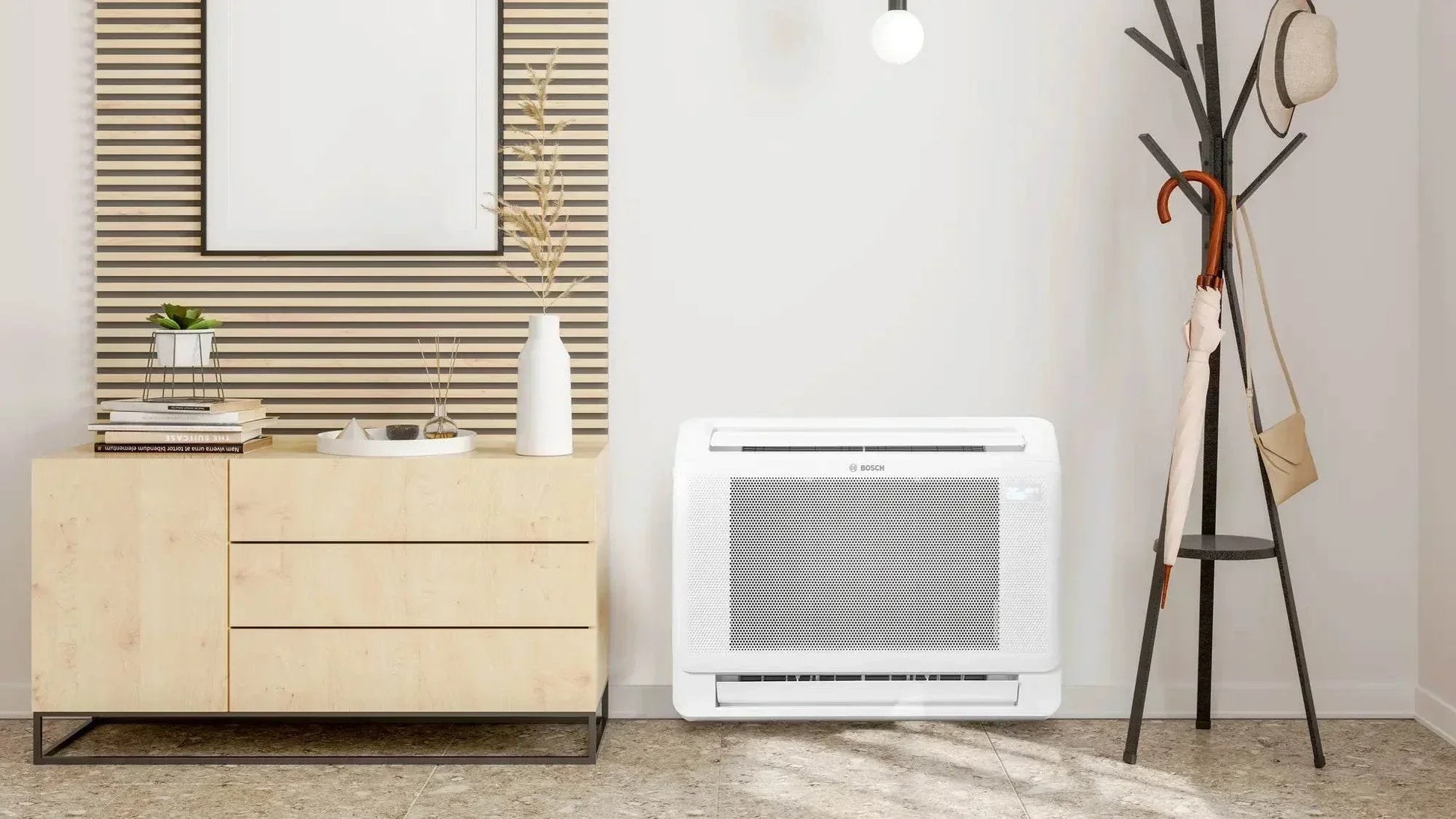 Bosch Climate 5000i M compact indoor console air conditioner unit installed on a white wall in a modern room with wooden cabinet and coat stand