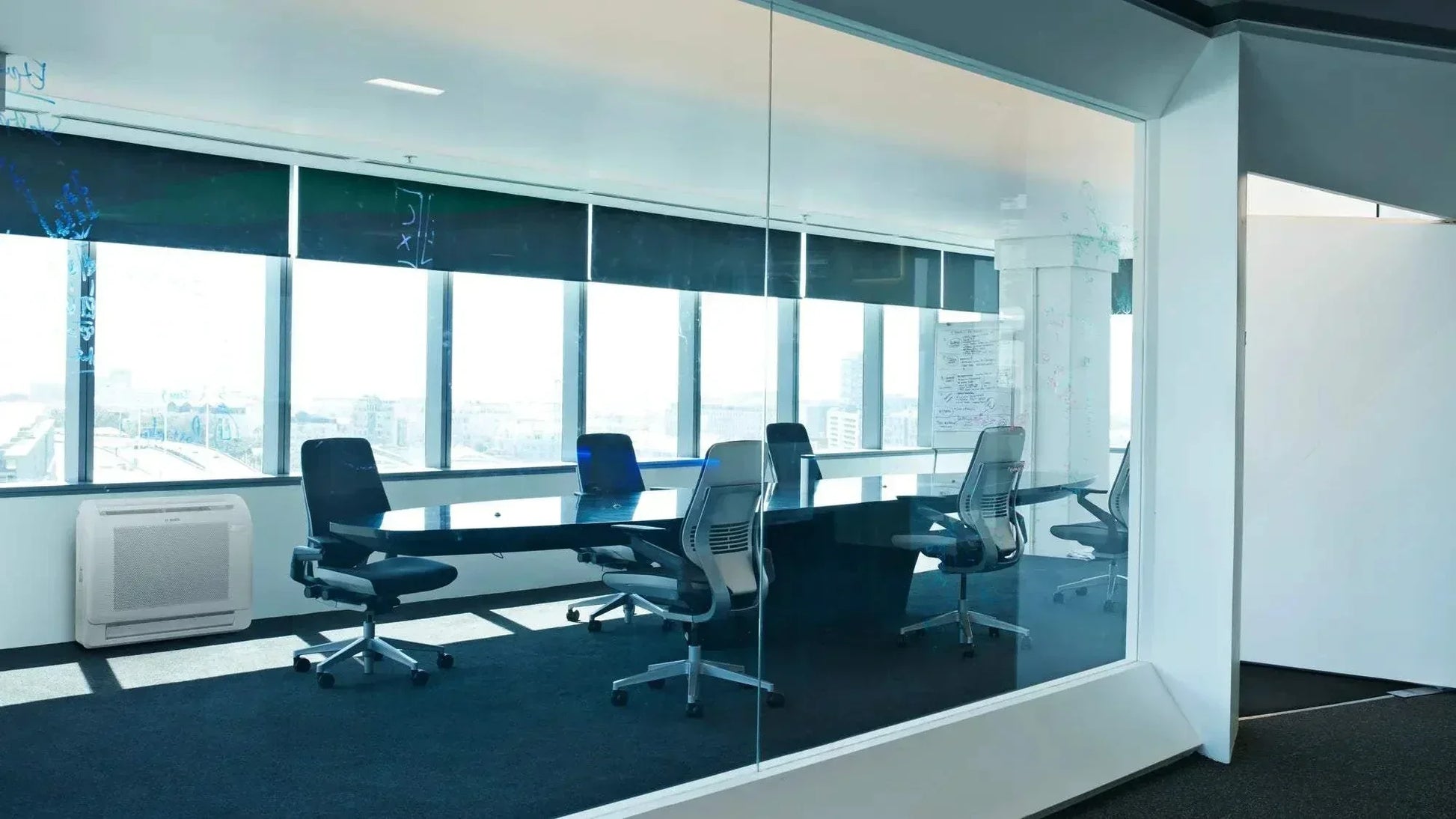 Bosch Climate 5000i M indoor console air conditioner unit in modern office meeting room with glass walls and chairs