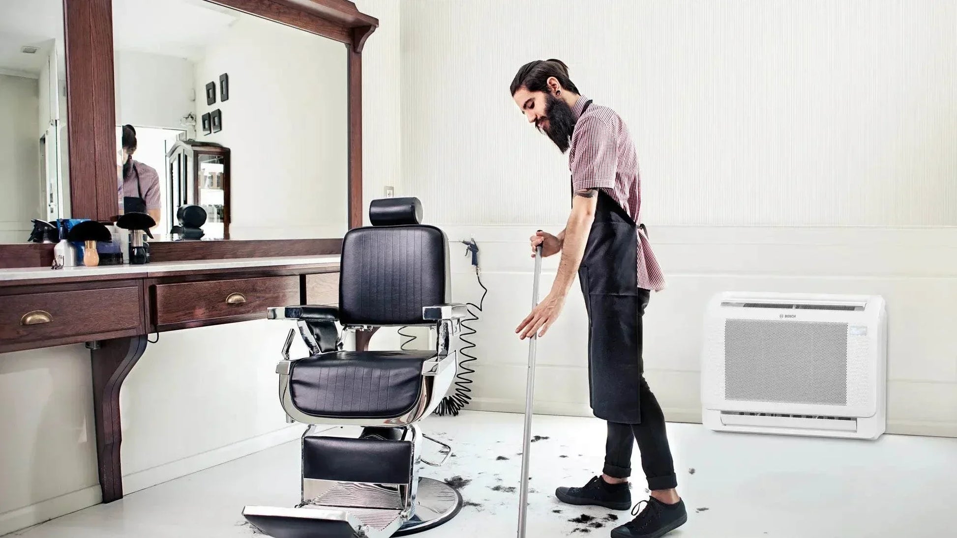Bosch Climate 5000i M indoor console air conditioner unit in a modern barbershop setting with compact wall-mounted design.