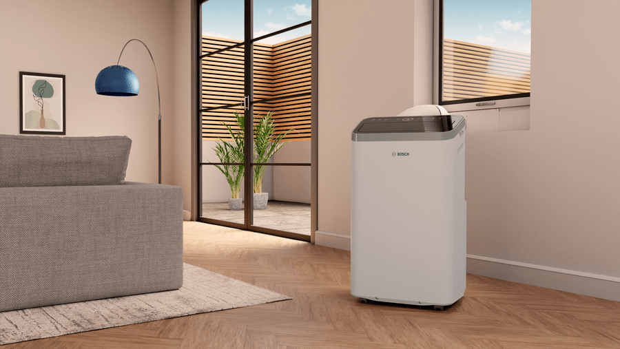 Mobile air conditioner Bosch Cool 4000 in modern living room near window, portable cooling unit with sleek design.