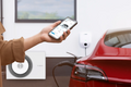 Person using Bosch Power Charge 7000i smart home wallbox charger to charge electric car with mobile app control.
