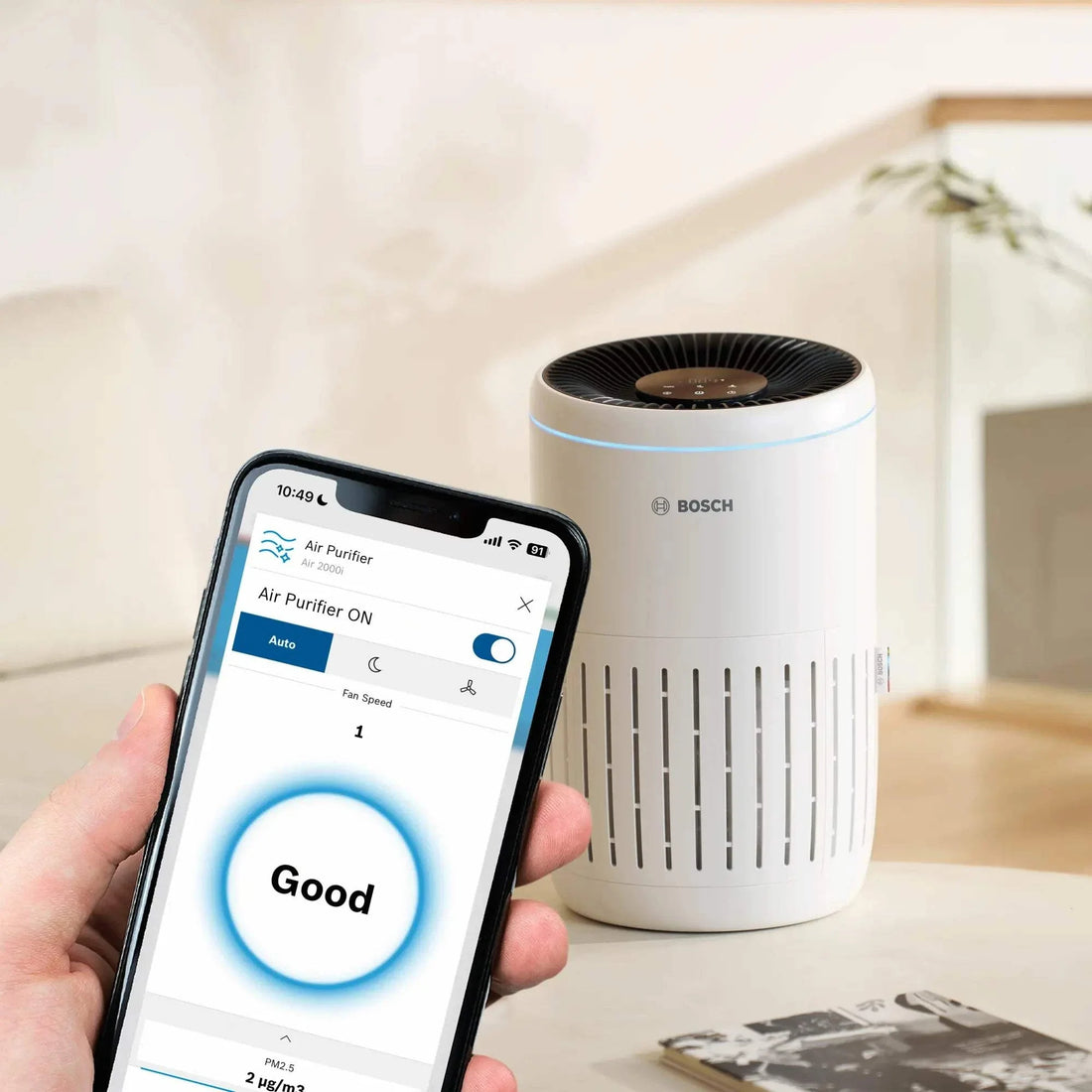 Bosch Air 2000i compact air purifier with 3-layer filtration and app control showing air quality "Good" on smartphone.