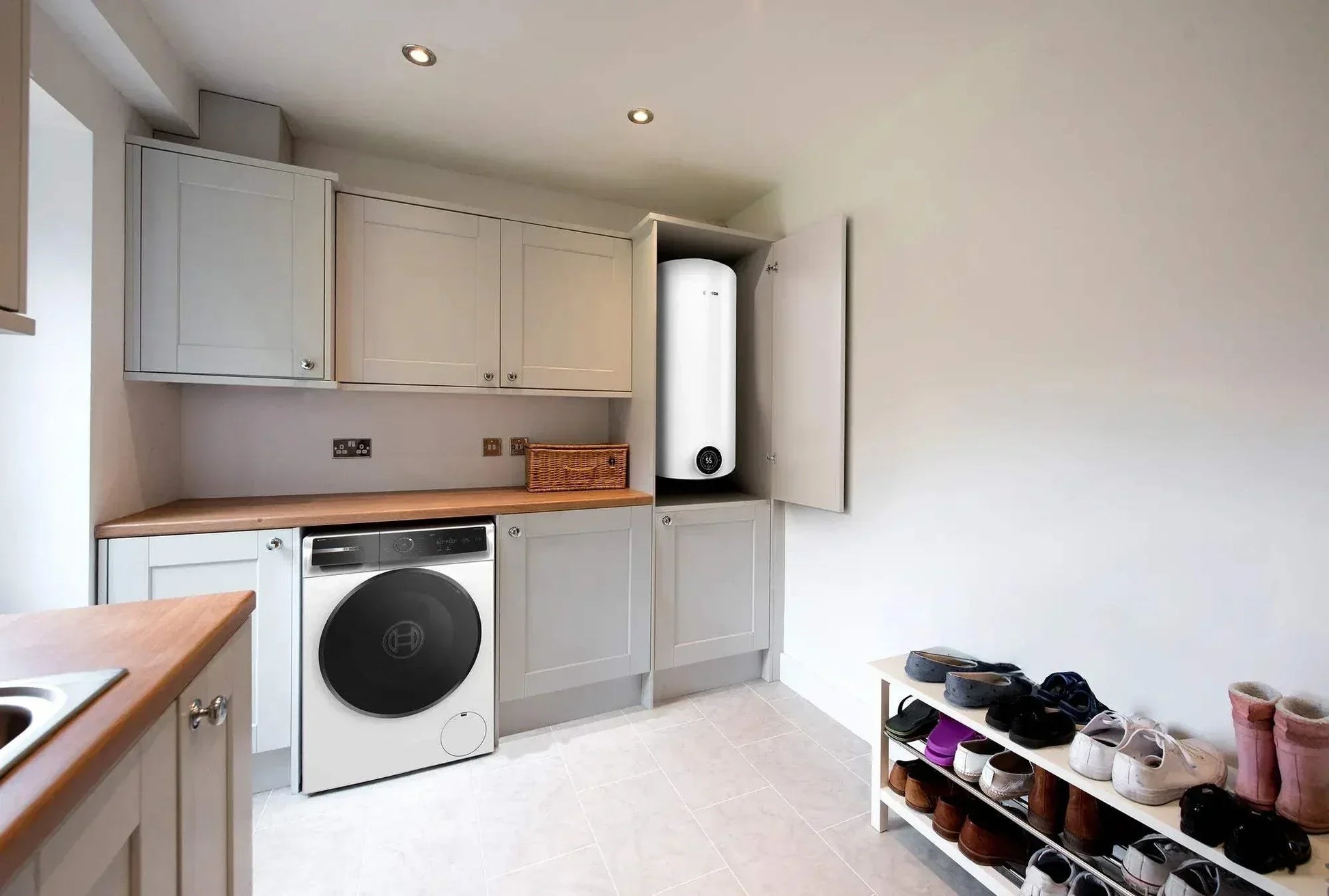 Vertical electric water heater Bosch Tronic 4000 T installed in kitchen cabinet with modern design and digital control panel